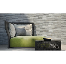 Szene mit einer Couch, Kissen und einem Tisch vor einer Steinwand