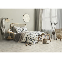 Helles Schlafzimmer mit Bett, Holzbeistelltisch und Rattansessel