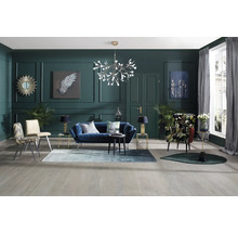 Wohnzimmer mit blauem Sofa, Sesseln, Teppich und Dekoration vor dunkelgrüner Wand