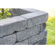 Nahaufnahme einer Mauer aus grauen Betonsteinen im Garten.