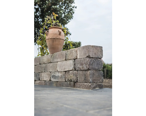 Eine Mauer aus Steinen mit einer Vase im Garten.