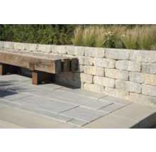 Außenbereich mit Mauer aus Steinblöcken, Bank aus Holz und Steinbodenplatten