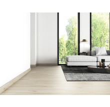 Heller Wohnraum mit Sofa, Teppich, Tisch und großem Fenster mit Blick ins Grüne.