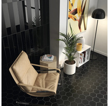 Modernes Interieur mit schwarzen, hexagonalen Bodenfliesen, beigem Sessel und minimalistischen Möbeln.