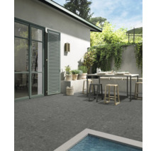 Terrasse mit Gartentisch und Stühlen, gefliest mit grauen Steinzeugfliesen.