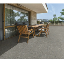 Terrasse mit Holztisch, Stühlen und grauen Bodenfliesen.