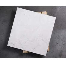 Quadratische, weiße Bodenfliese mit Marmorierung auf Holzpalette