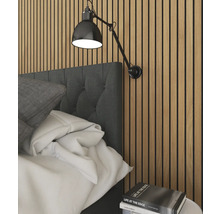 Schlafzimmerszene mit Bett, Wandlampe und Bücherstapel