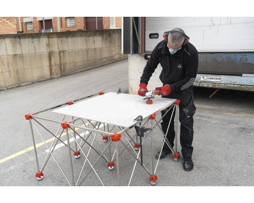 Fliesenschneider mit Fliese auf Schneidetisch und Arbeiter