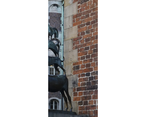 Skulptur der Bremer Stadtmusikanten vor einer Backsteinmauer.