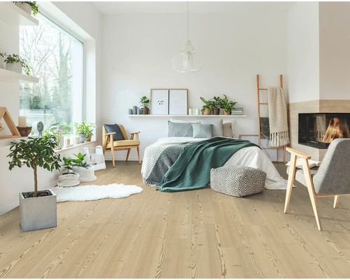 Helles Schlafzimmer mit Laminatboden in heller Holzoptik, ausgestattet mit Bett, Sesseln, Zimmerpflanzen und einem gemütlichen Kamin.