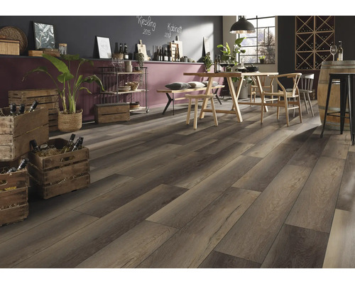 Dunkler Laminatboden in Holzoptik in einem rustikalen Raum mit Holztisch, Stühlen und Weinkisten. Die Atmosphäre ist hell und einladend.