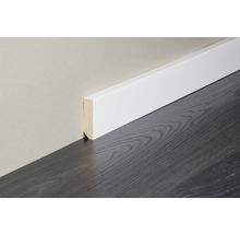 Weiße Sockelleiste mit Holzkern an einer hellen Wand auf dunklem Bodenbelag mit Holzoptik.