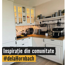 Helle Küche in L-Form mit weißen Schränken, Holz-Arbeitsplatte, Mosaikfliesen-Rückwand und Küchengeräten wie einer Kaffeemaschine.