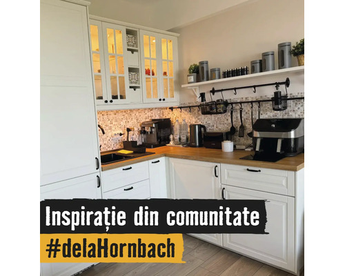 Helle Küche in L-Form mit weißen Schränken, Holz-Arbeitsplatte, Mosaikfliesen-Rückwand und Küchengeräten wie einer Kaffeemaschine.