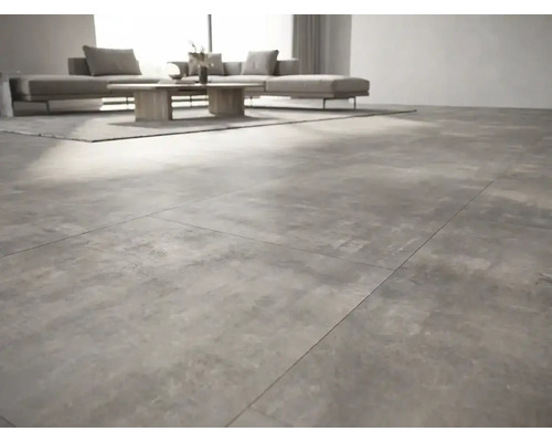Modernes Wohnzimmer mit großformatigen Bodenfliesen in Betonoptik, grauem Sofa und Holztisch.
