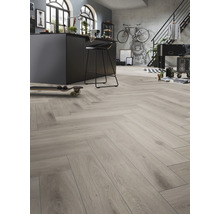 Innenaufnahme eines Raumes mit hellem Holzboden im Fischgrätmuster, einer Kücheninsel und verschiedenen Möbeln.