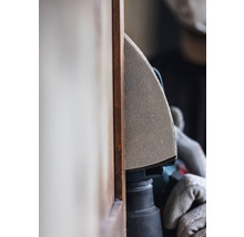 Detailansicht einer Person, die mit einem Schleifgerät an einem Holzstück arbeitet.