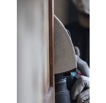 Eine Person schleift mit einem Multischleifer ein Holzbrett.