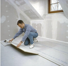 Mann verlegt Trockenestrich in einem Dachgeschossraum