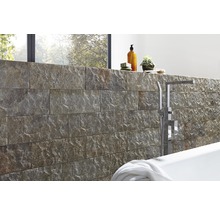 Badezimmergestaltung mit Natursteinwand, Badewanne und Armaturen