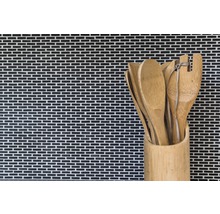 Holzlöffel und Spatel in einem Bambusbehälter vor einer Mosaikwand