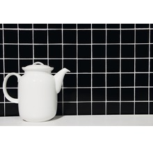 Teekanne aus Keramik vor quadratischem Fliesenmuster