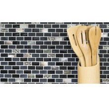 Küchenutensilien aus Holz in einem Behälter vor einer Mosaikwand