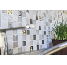 Nahaufnahme einer Wand mit Mosaikfliesen und einer Topfpflanze.