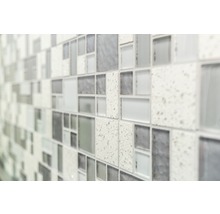 Nahaufnahme einer Wand mit Mosaikfliesen in unterschiedlichen Grautönen und Texturen.