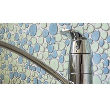 Nahaufnahme eines Wasserhahns vor einer Wand mit Mosaikfliesen in Kieselmuster