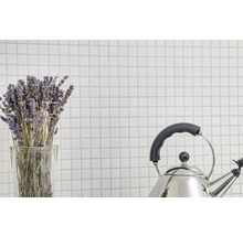 Bündel Lavendel in einem Glas und ein Edelstahlkessel vor einem Hintergrund aus weißen Fliesen.