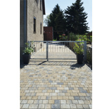 Einfahrt mit Pflastersteinen und Metalltor vor einem Haus
