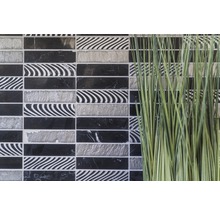 Dekorative Mosaikfliesen in Schwarz, Weiß und Grau neben Ziergras