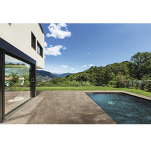 Terrasse mit Steinplatten neben einem Schwimmbecken und einem Haus