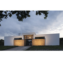 Modernes Haus mit Natursteinfassade und großen Fensterflächen.