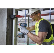 Handwerker verwendet einen Akku-Schlagschrauber an einem Fensterrahmen auf einer Baustelle.