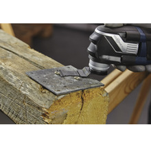 Oszillierendes Elektrowerkzeug schneidet eine Metallplatte, die an einem Holzstück befestigt ist.