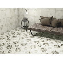 Raumansicht mit Bodenfliesen und Wandfliesen im Blumendesign, ergänzt durch eine Sitzbank, einen Hocker und eine Lampe