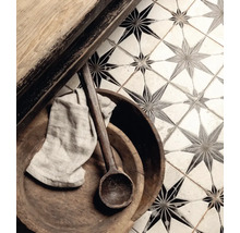 Detailaufnahme von Bodenfliesen mit Sternmuster, kombiniert mit Holzelementen, einem Holzlöffel und einem Tuch.