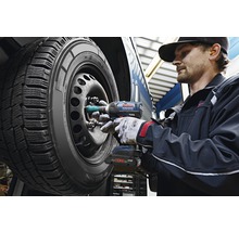 Ein Mechaniker verwendet einen Akku-Schlagschrauber, um die Radmuttern an einem Autoreifen zu befestigen