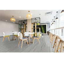 Heller Raum mit Tischen, Stühlen und Regalen mit Pflanzen auf grauem Holzboden