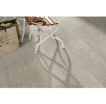 Verlegte Bodenfliesen im Innenbereich mit Schattenwurf eines Stuhls.