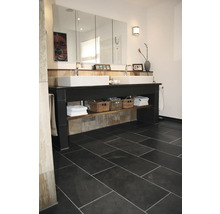 Badezimmer mit Doppelwaschtisch, Spiegel und dunklem Fliesenboden.