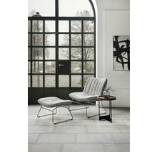 Modernes Wohnzimmer mit Sessel, Fußhocker und Beistelltisch vor einem Sprossenfenster.