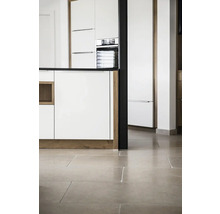 Kücheninneneinrichtung mit weißen Schränken, dunkler Arbeitsplatte und Steinboden