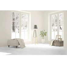 Heller Raum mit Fensterblick auf verschneite Bäume, Hocker, Stehlampe und Dekoration