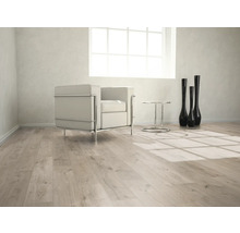 Heller Raum mit Laminatboden, Sessel, Tisch und Dekovasen.