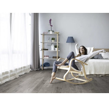 Heller Wohnraum mit Holzboden, Schaukelstuhl und einer entspannten Frau