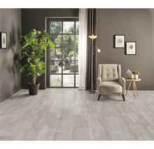 Wohnzimmer mit hellem Bodenbelag, Sessel, Stehlampe und Topfpflanze